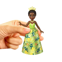 Princess doll in green patterned dress with crown, posed in a hand