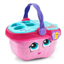 Pink toy picnic basket with purple handle and teal activity tray, close-up