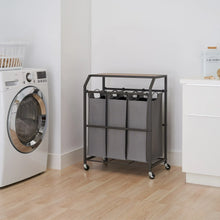 Laundry cart with three gray fabric bags and flip-up top on caster wheels