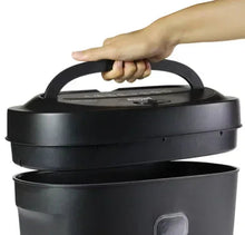 Dark gray cross-cut paper shredder with handle, hand holding top