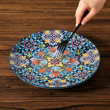Blue floral patterned ceramic plate with colorful ornamental center, with utensils