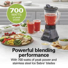 Countertop blender with red smoothie in clear jar and smaller smoothie cups