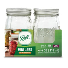 Clear glass mini mason jars with silver lids behind a green product box