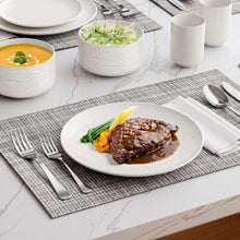White speckled bowl and round dinner plate with utensils on a placemat