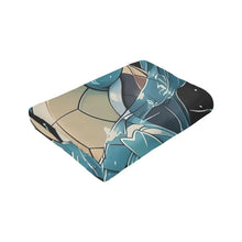 Folded flannel throw blanket with teal turtle character and black splash pattern