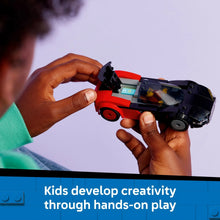 Red and black EV sports car toy held by hands with seated driver minifigure
