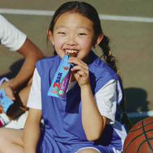 Child eating a Zbar chocolate chip snack bar outdoors