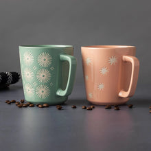 Mint green and blush pink mugs with white starburst motifs and thick curved handles