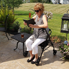 Black rollator walker with padded seat and four wheels outdoors