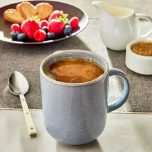 Decaf coffee in blue mug with crema, berries and cookies on plate
