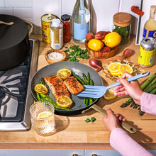 Black non-stick fry pan with food inside, light wood handle