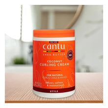 Cantu Coconut Curling Cream jar on tabletop, orange lid and red front label