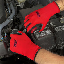 Red knit work gloves with black nitrile-coated palms in an engine bay