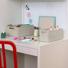Beige woven plastic storage baskets with open tops holding desk supplies