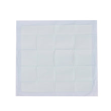 Square white dog training pad with quilted grid texture inside clear packaging