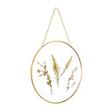 Round glass wall decor with gold frame, hanging chain, and dried pressed floral sprigs
