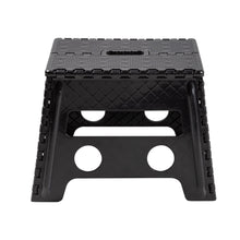 Black plastic folding step stool with textured top and two circular cutouts