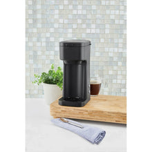 Matte single-serve coffee maker on counter with cup beneath spout, black matte
