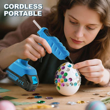 Blue cordless hot glue gun held by hand for crafting projects with glue