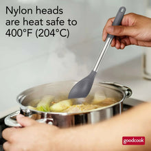 Hand holding dark gray nylon spoon with stainless handle over a pot