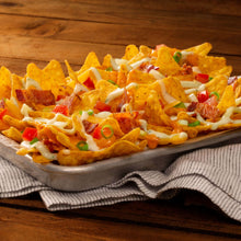Nachos on a tray with melted cheese, tomatoes, onions, and green garnish
