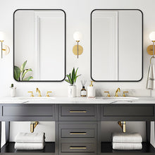 Bathroom mirrors set with black rounded frames above a double sink vanity.