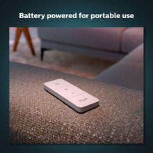 White Philips Hue dimmer switch with power icon and three controls, on tabletop