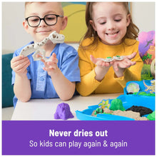 Children holding white dinosaur fossil molds over a blue sand tray