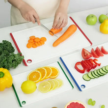 Large plastic cutting board with multicolor border, used for slicing vegetables