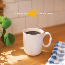 White ceramic mug filled with dark ground coffee on a wooden table