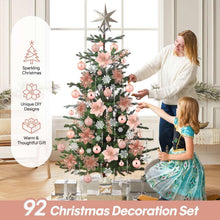 Christmas decoration set on a tree: pink baubles, glitter flowers, and white snowflake ornaments