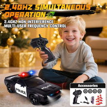 Child holding a black RC remote next to a black police drift car with LED lights