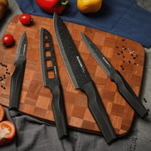 Kitchen knife set with speckled black blades and black handles arranged on a board