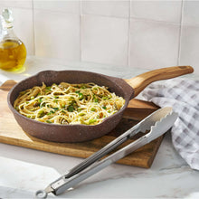 Brown speckled fry pan with wooden handle, filled with noodles