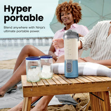 Blue portable personal blender with clear cup, gray lid, filled with ice and fruit