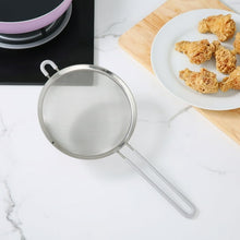 Fine mesh stainless steel strainer tilted with cooked food and long handle