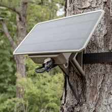 Solar power pack mounted on tree with angled dark solar panel and attached cable