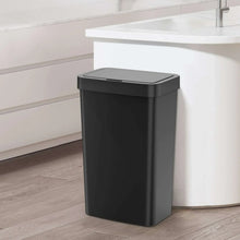 Black automatic trash can standing on the floor with rectangular top lid closed