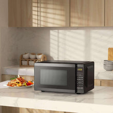 Black countertop microwave oven on kitchen counter with door closed and display lit