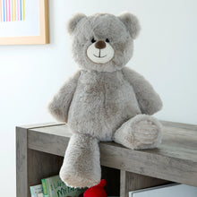 Gray bear plush with stitched smile and paw pads, sitting upright