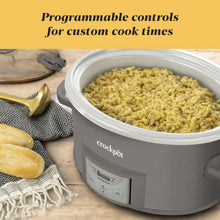 Grey oval slow cooker filled with food and programmable control panel