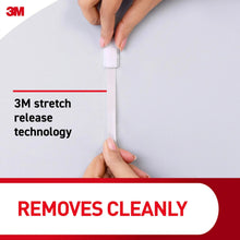 Hand applying a foam adhesive strip to a smooth wall surface
