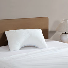 White cooling pillow with embossed circles and U-shaped cutout on bed
