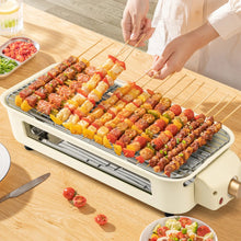Electric indoor grill with skewers on the rack and food on the ridged grate, beige body