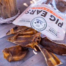 Smoked pig ear dog treats, brown curled chews with treat pouch partially visible