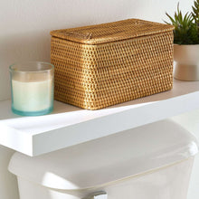 Brown rattan organizer basket with closed lid, woven texture and curved top edge.
