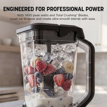 Blender pitcher filled with ice and fruit, clear jug and blade assembly visible