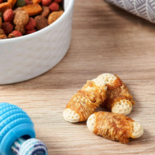 Biscuit-wrapped chicken dog treats with peanut butter flavor on a wooden floor