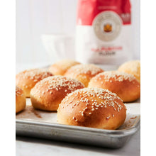 Unbleached all-purpose flour with sesame buns on tray, flour bag in background