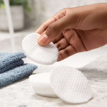 Cotton rounds in hands, showing stacked white round pads.